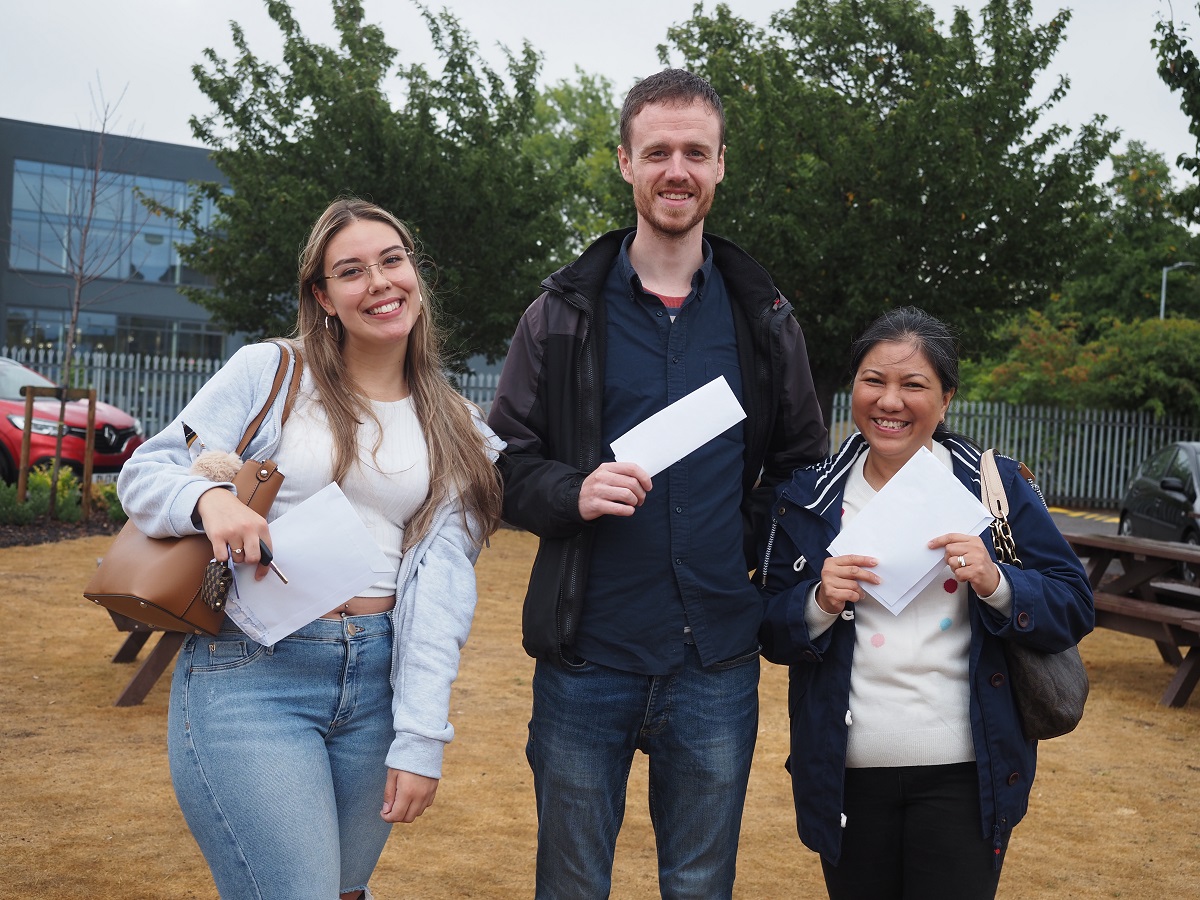 Two women and a man with their GCSE results - Bebiana, Ryan and Thi celebrate after collecting their GCSE Results
