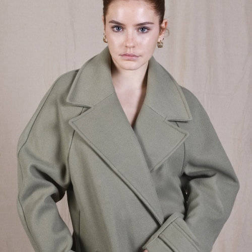 person posing to the camera with a big greenish jacket