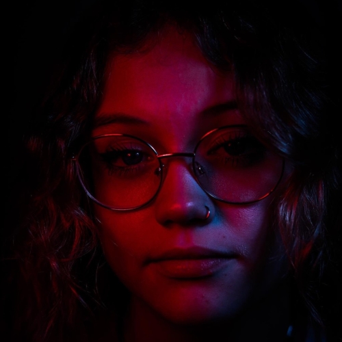 Close up photo of a person with glasses with a red glow