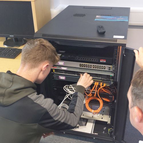 Photo of two people inspecting and installing a drive into a server rack